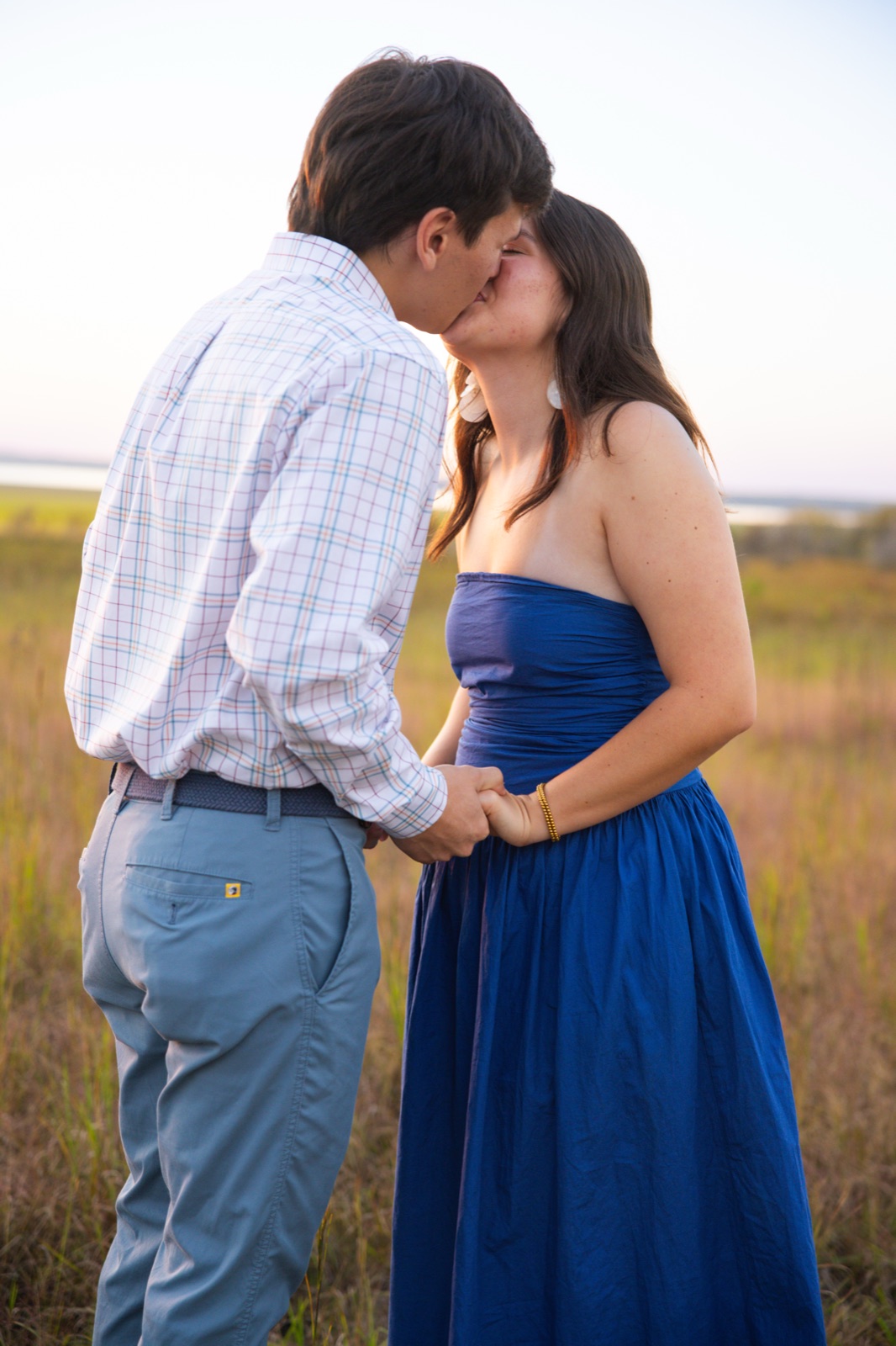 Newly engaged couple kissing in a golden field at sunset, engagement photography in north Mississippi