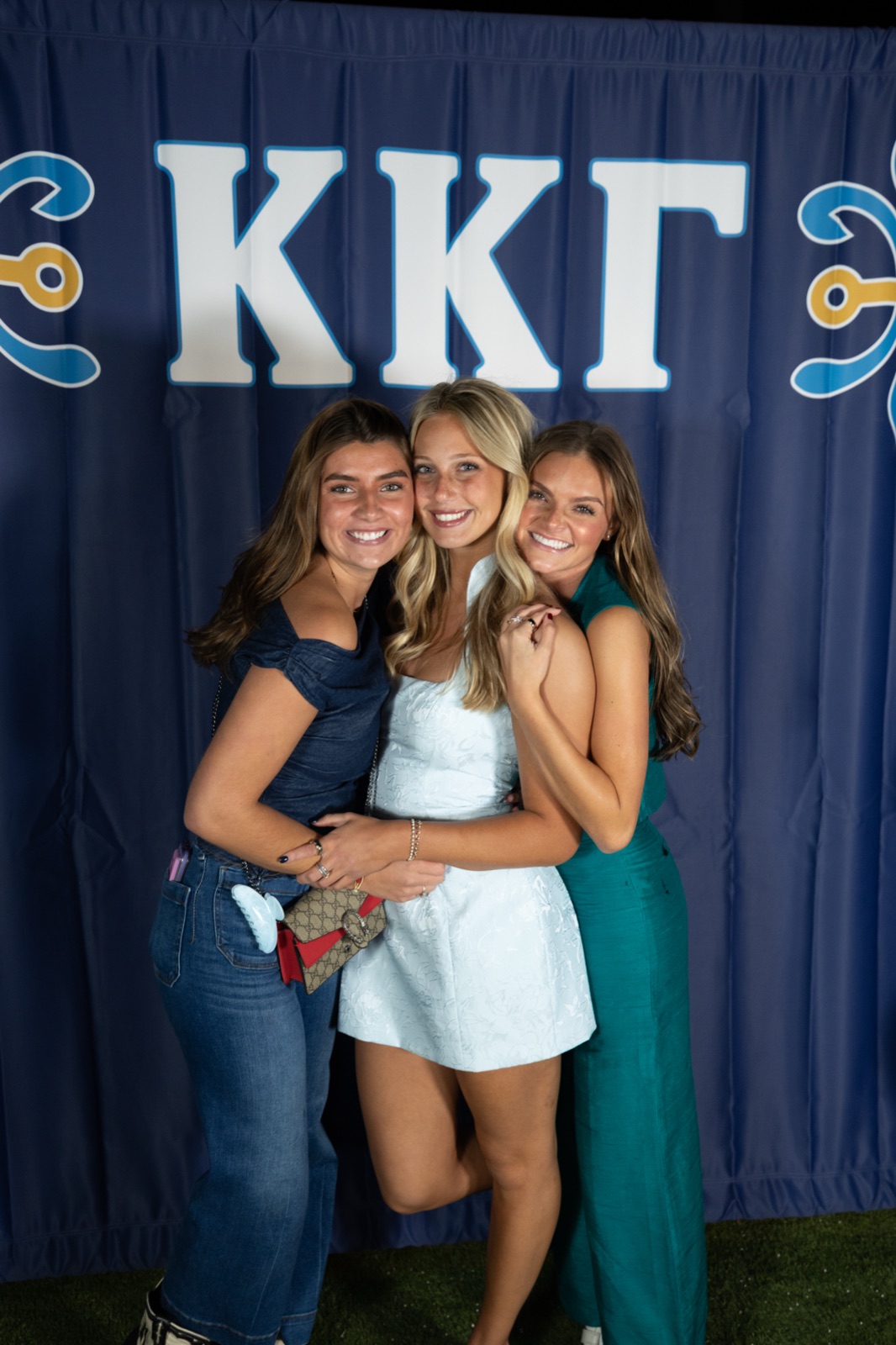 Three friends hugging at the Kappa Kappa Gamma backdrop during parents weekend, Oxford MS