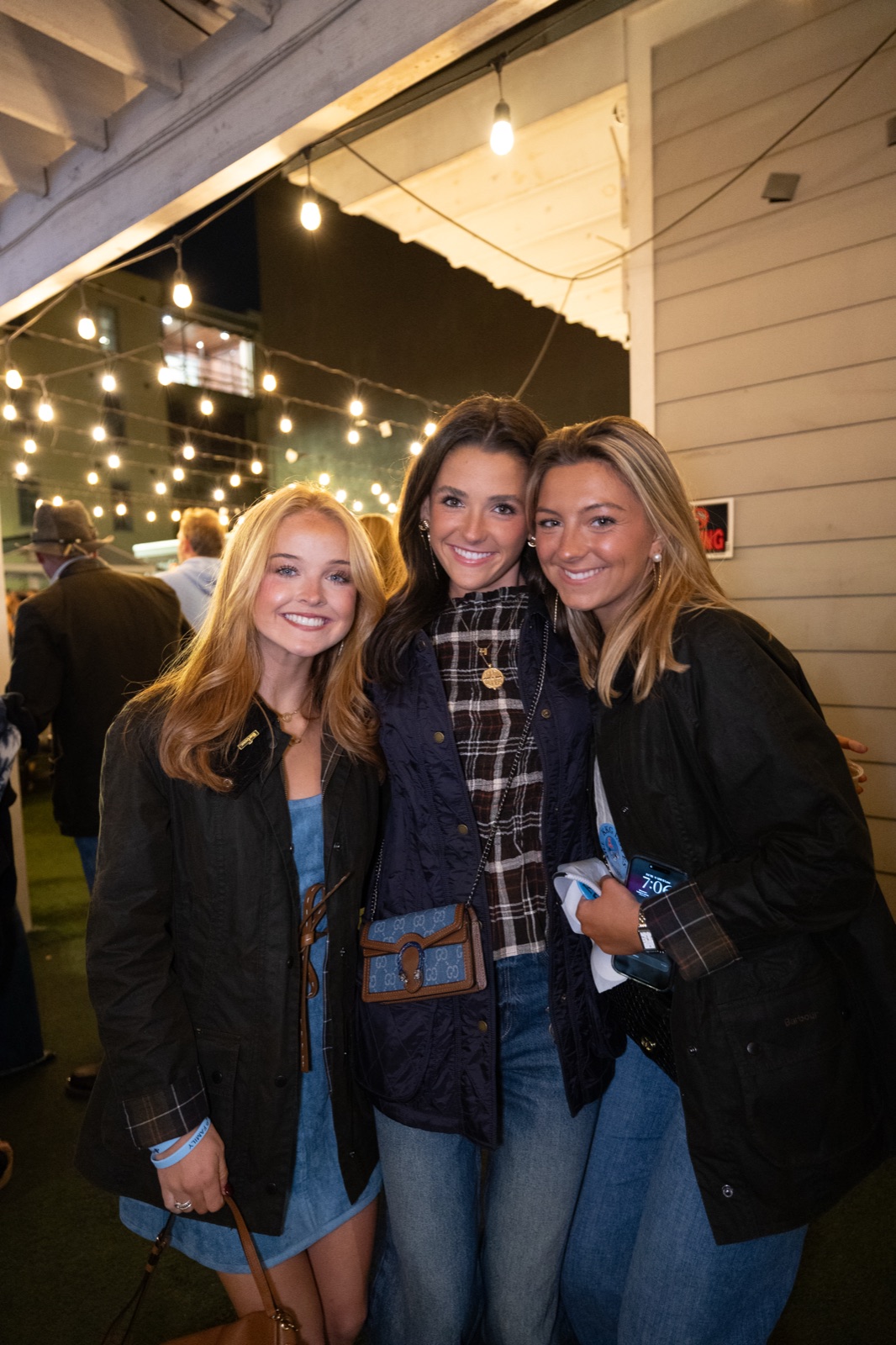 Three friends under string lights at Kappa Kappa Gamma parents weekend, Oxford, Mississippi