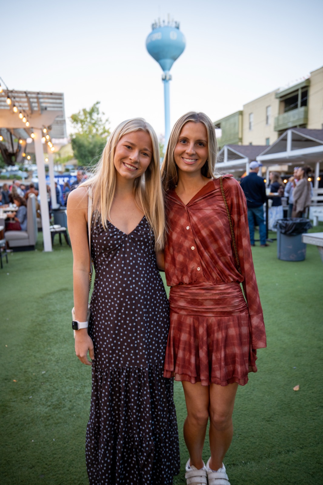 Two friends on the lawn at Harrison's during Kappa Kappa Gamma parents weekend, the Oxford water tower behind them