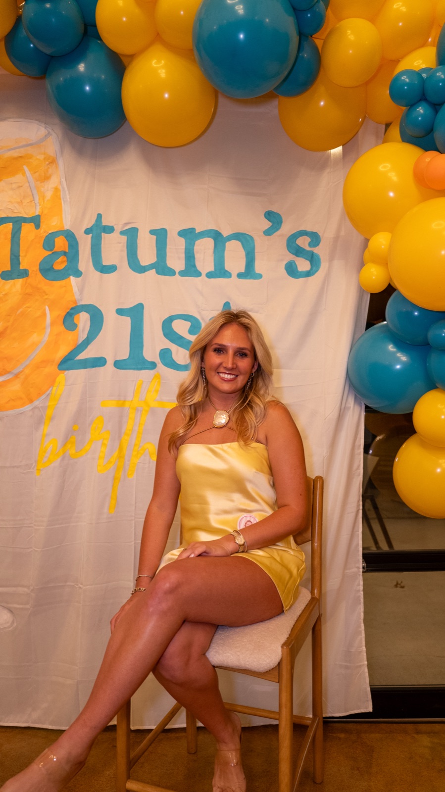 Birthday girl seated in front of a hand-painted 21st birthday banner at a party in Oxford, MS